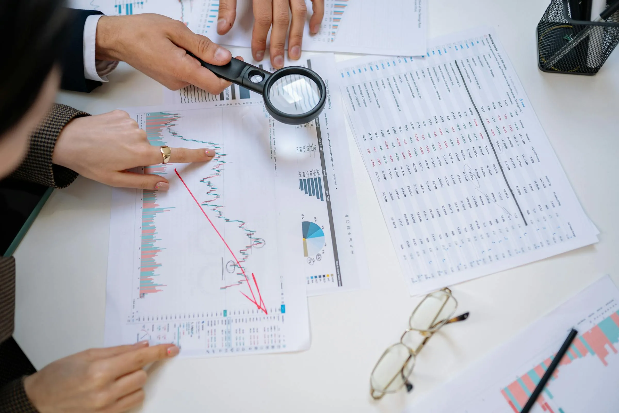 Business professionals examining financial documents with magnifying glass for detailed analysis